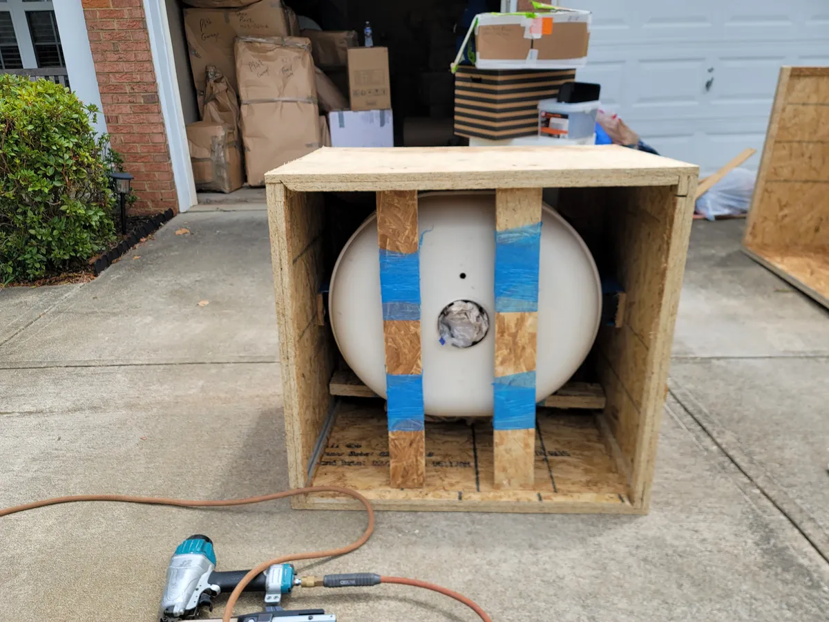 Open crate with a round pedestal blocked and taped into place, brad nailer and air line on the driveway
