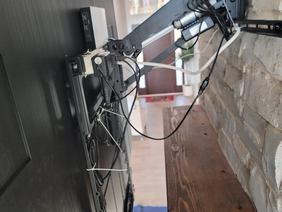 Close view of a full-motion articulating TV mount arm anchored into a stone fireplace
