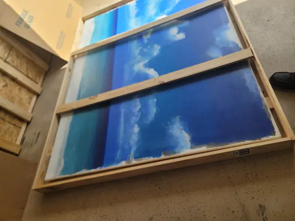 Framed painting secured inside a custom wood travel frame beside a carton marked fragile glass