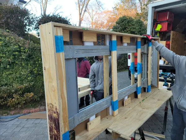 Technician building a custom wooden crate around a large framed piece marked fragile glass