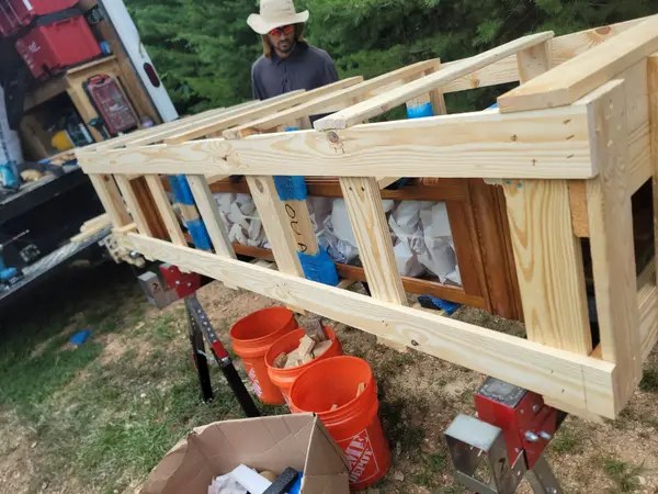 Technician assembling custom wooden crate frames on sawhorses beside a work truck