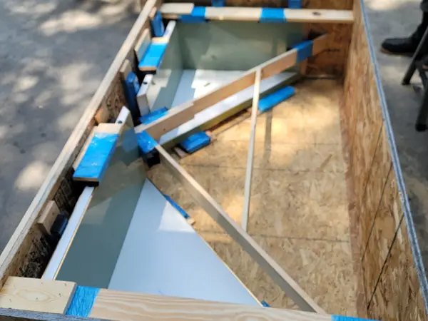 Open crate interior showing a framed glass panel padded and taped against internal wood bracing