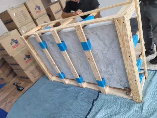 Marble tabletop braced inside a custom wood crate frame beside stacked moving cartons