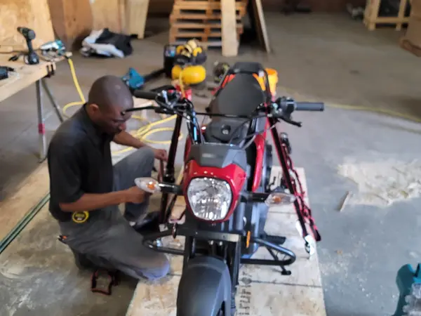 Technician preparing a motorcycle for custom crating on a plywood base in a warehouse