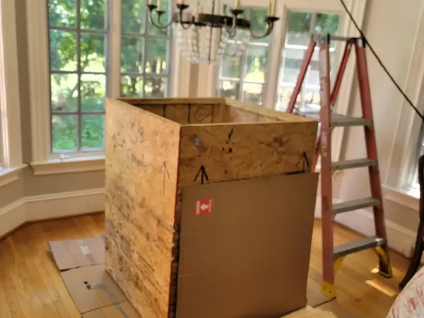 Tall custom plywood crate built on site in a bay-window room