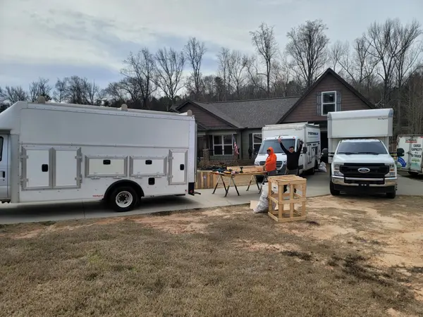 Enclosed work trailer and box truck parked outside a home before an installation job