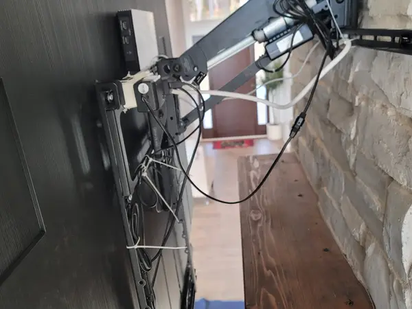 Close view of a full-motion articulating TV mount arm anchored into a stone fireplace