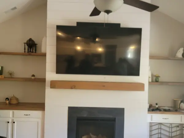 Flat-screen TV mounted on a shiplap fireplace wall with built-in shelving