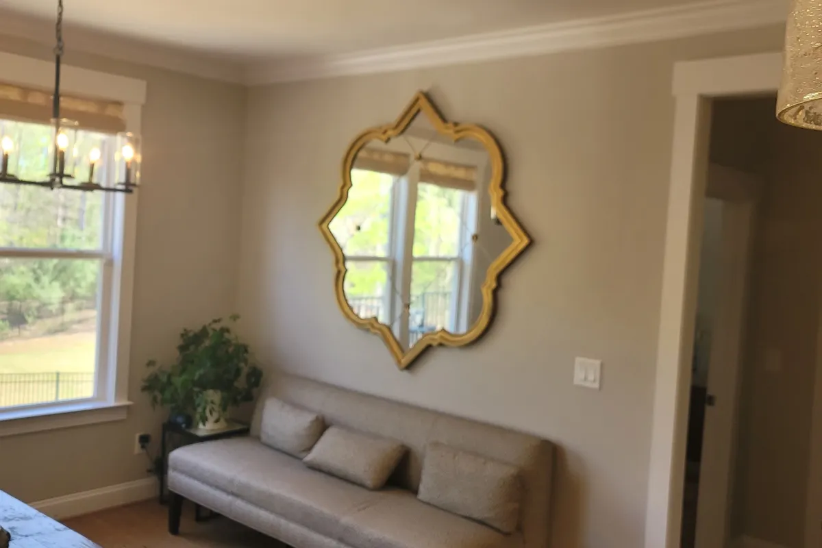 Decorative gold-framed mirror hung centered on a living room wall above a sofa