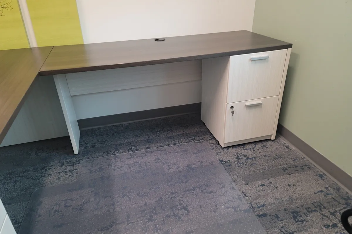 Assembled office desk with attached file drawer unit set up on a patterned rug